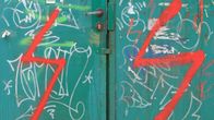 Graffiti med röda blixtar på ett grönt nedklottrat metallskåp.