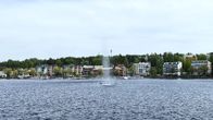 Iso suihkuläde järvessä. Taustalla taloja.