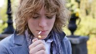 A young person lighting a cigarette.
