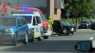 Två bilar har kolliderat i en korsning, med polisbil, ambulans, bärgningsbil och flera personer på platsen.