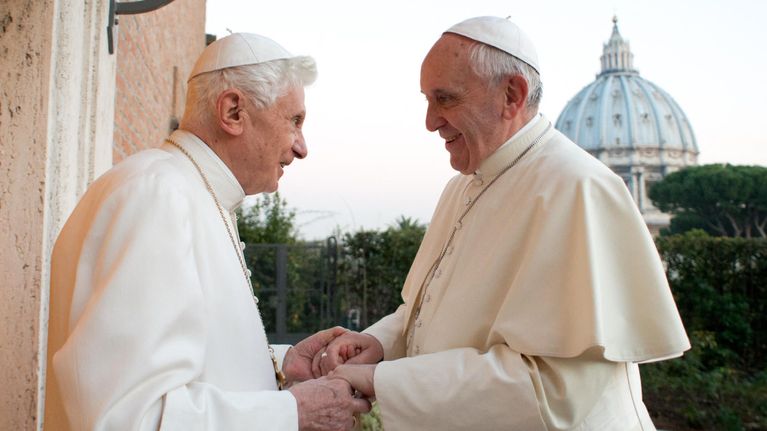 Paavi Benedictus ja paavi Franciscus pitävät toisiaan käsistä.