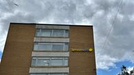 Kerrostalo Vaasan keskustassa, jossa toiseksi ylimmän ikkunan vieressä Lemonsoft-valomainos. Tummia pilviä taustalla.