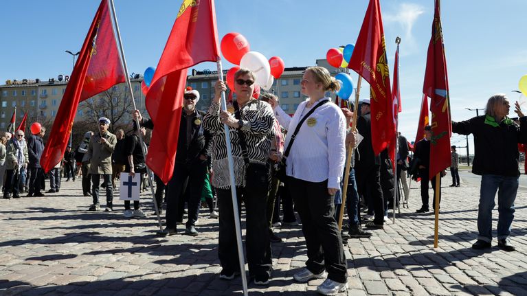 Vappumarssille osallistuvia ihmisiä Hakaniementorilla. Punaliput liehuvat.