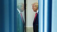 Donald Trump går längs en korridor. Hans spegelbild syns på väggen.