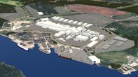 En industriell anläggning breder ut sig längs med en vattendrag med flera byggnader, vägar och kajer synliga.
