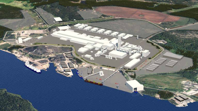 En industriell anläggning breder ut sig längs med en vattendrag med flera byggnader, vägar och kajer synliga.