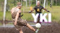 Kaksi miestä pelaa suojalkapalloa, kuvan päällä YKI-teksti.