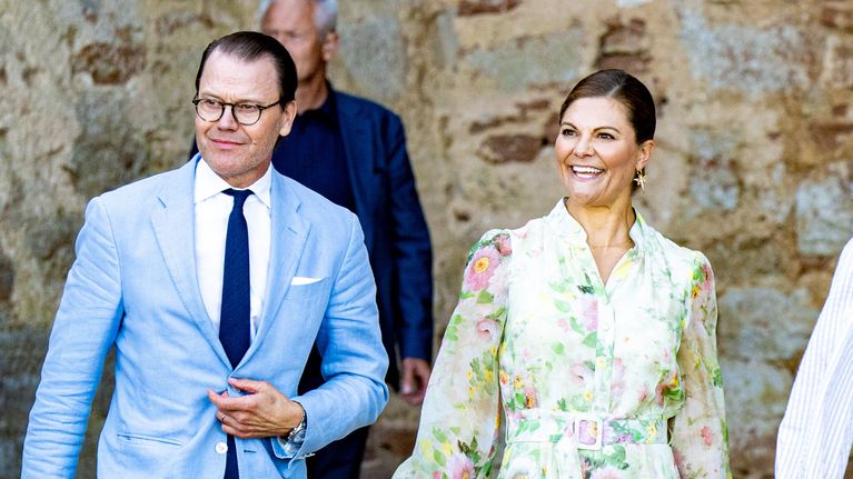 Prins Daniel och kronprinsessan Victoria går med slottsruiner i bakgrunden.