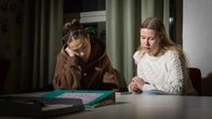 Kaksi abiturienttia odottavat ylioppilaskokeiden tuloksia pöydän ääressä.
