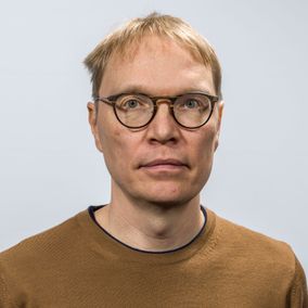 Vaaleatukkainen keski-ikäinen mies pyöreät silmälasit päässään.