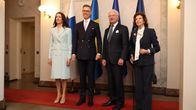 Four people pose in front of Finnish, Swedish and EU flags.