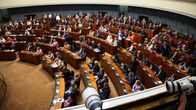Kansanedustajat asettuvat istumaan paikoilleen eduskuntasalissa.
