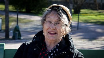Leena Kosonen katsoo kameraan ylioppilaslakki päässä.