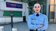 Poliisin asuun pukeutunut Sini Strömberg poseeraa kädet ristissä kameralle. Taustalla Poliisiammattikorkeakoulun sisäänkäynti.