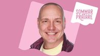 En man med väldigt kortsnaggat hår tittar rakt in i kamerna med ett brett leende så att man ser tänderna. Bakgrunden är vispgrötsfärgad och i högra hörnet står det sommarpratare.