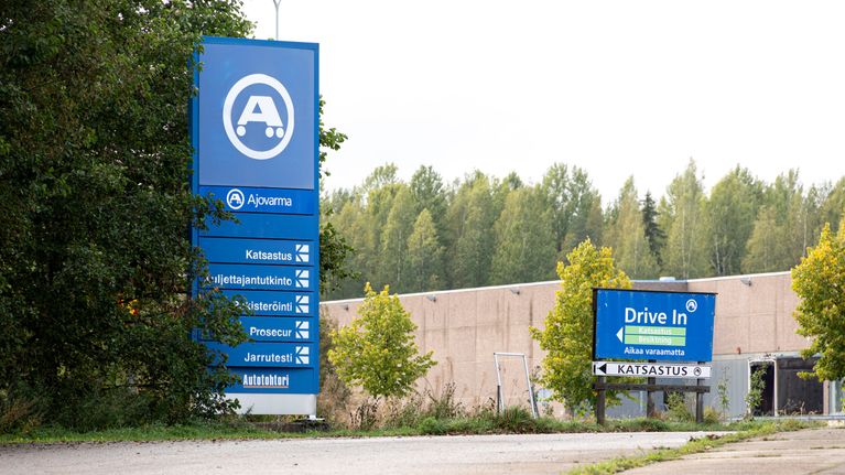 Kuvassa on Ajovarma-katsastusaseman piha-alue ja kaksi opastetta.