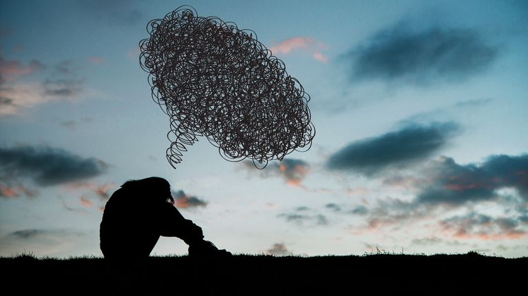 Photo shows a silhouette of a person looking sad.