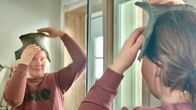 Nainen asettelee kolttasaamelaisen päähinen pohjaa otsalleen. 
