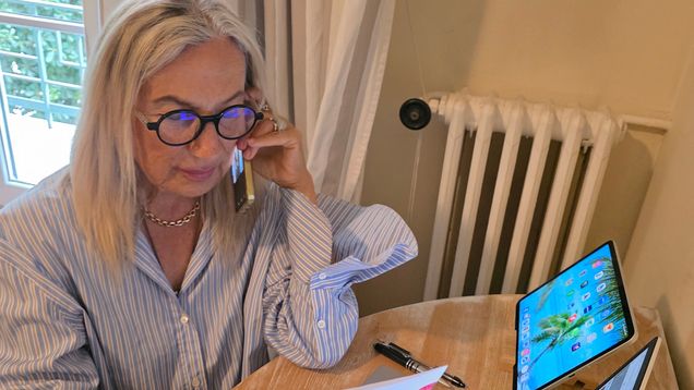 A woman speaks on the phone while looking at documents.