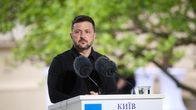 Zelenskyj står vid ett podium utomhus med allvarlig min. 