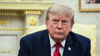 Donald Trump istuu vakava ilme kasvoillaan.