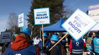 Tamkin lakossa olevia plakaatein varustettuja työntekijöitä.