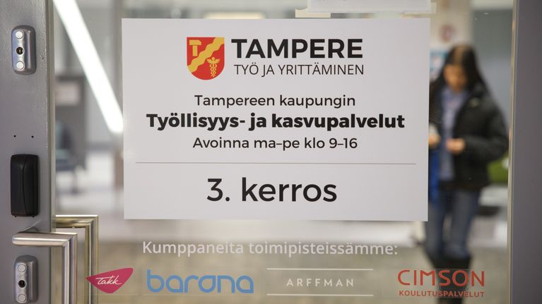Työllisyyspalveluiden lasinen ovi, jonka takana nuori nainen.
