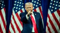 Donald Trump seisoo Yhdysvaltain lippujen edessä ja osoittaa sormellaan kohti katsojaa.