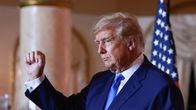 Donald Trump iklädd kostym höjer näven och ser allvarlig ut.