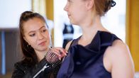 Vaatesuunnittelija Saaga Lamusuo asettelee Essi Soljeen juhlamekkoa.