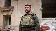 Ukrainas president Volodymyr Zelenskyj står bland ruiner med en allvarlig min.