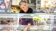En person står bakom en glasdisk och serverar glass i en restaurang.
