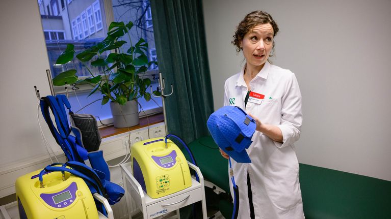 Läkaren Renske Altena förevisar medicinsk utrustning och håller i en blå hjälm.
