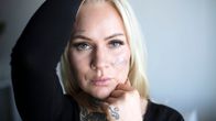 Joanna Janhonen kehystää käsillään kasvojaan ja katsoo suoraan kameraan.