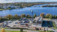 Rakennustyömaa ja nosturi, taustalla joki ja kerrostaloja.