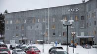 A large grey modern building with the word AALTO in white and about a dozen cars parked in the snow in front of it.