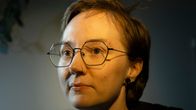 Lyhytkiuksinen silmälaispäinen nainen hupparissa.