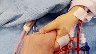 A mother holds her child's hand in the hospital. 