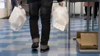 Mies kantaa kahta muovikassia Jyväskylän ruoka-avussa. Kassit ovat täynnä avustusruokaa. 