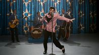 Elokuvahahmo Elvis tanssii mikrofonin edessä lavalla, taustalla yhtye.