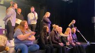 Nuoria istumassa teatterilavan reunalla.