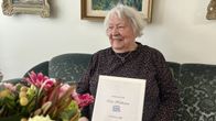 Eila Hukkanen diplominsa kanssa sohvalla asunnossaan Kouvolassa.