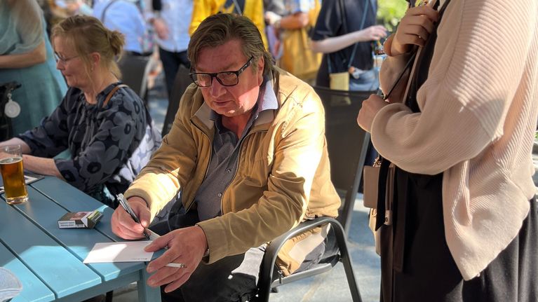 Aki Kaurismäki kirjoittaa nimikirjoitusta japanilaiselle turistille. 