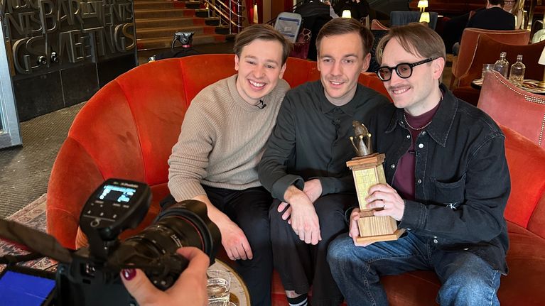 Jakob Norrgård, Kevin Holmström och Axel Åhman sitter i en soffa och håller i ett pris.