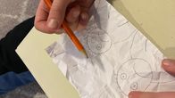 Kuvassa lapsi piirtää surullisia kasvoja paperille. Kuvituskuva.
