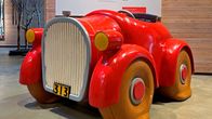 Punainen, puinen auto museon näyttelytilassa.