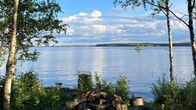 Rannalla olevan nuotiopaikan taustalla näkyy kesäinen ja auringonpaisteinen järvi.