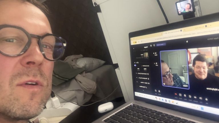 Mikko "Peltsi" Peltola katsoo kuvaan sekaisessa huoneessa. Tietokoneen näytöllä on videopuhelu josta kurkistaa myös Juuso Myllyrinne.
