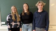 Laanilan yläkoulun oppilaat Pieta Tikkanen, Milja Marjamäki Verneri Sundström seisovat liitutaulun edessä ja katsovat kameraan. 