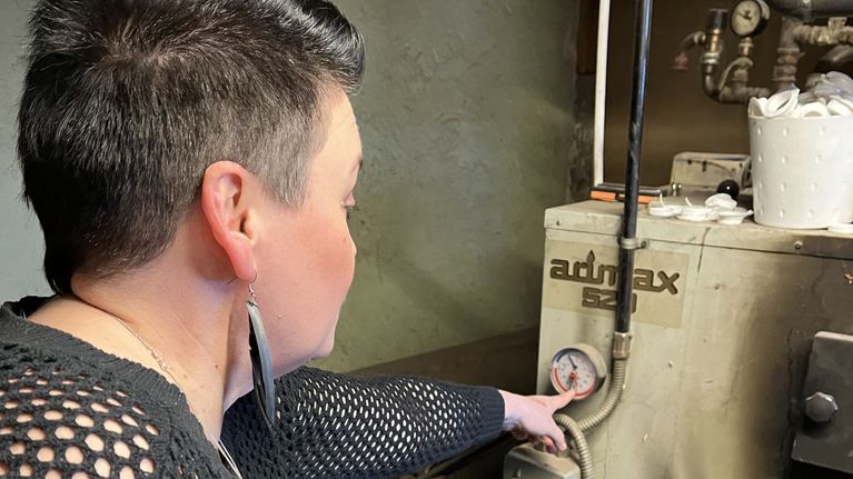 Minna Immonen osoittaa keskuslämmityskattilan mittaria.